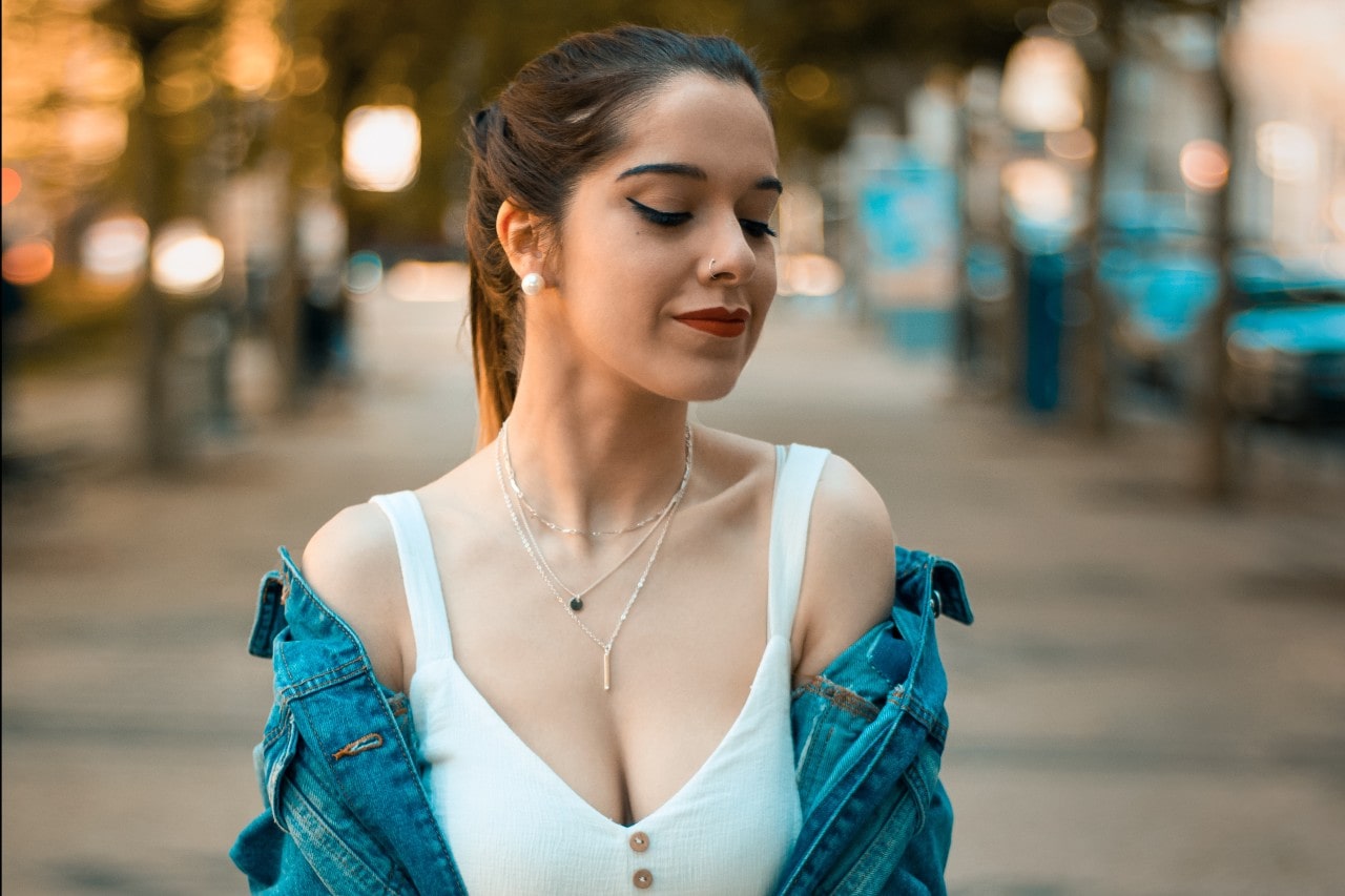 A woman outside wearing three white gold necklaces