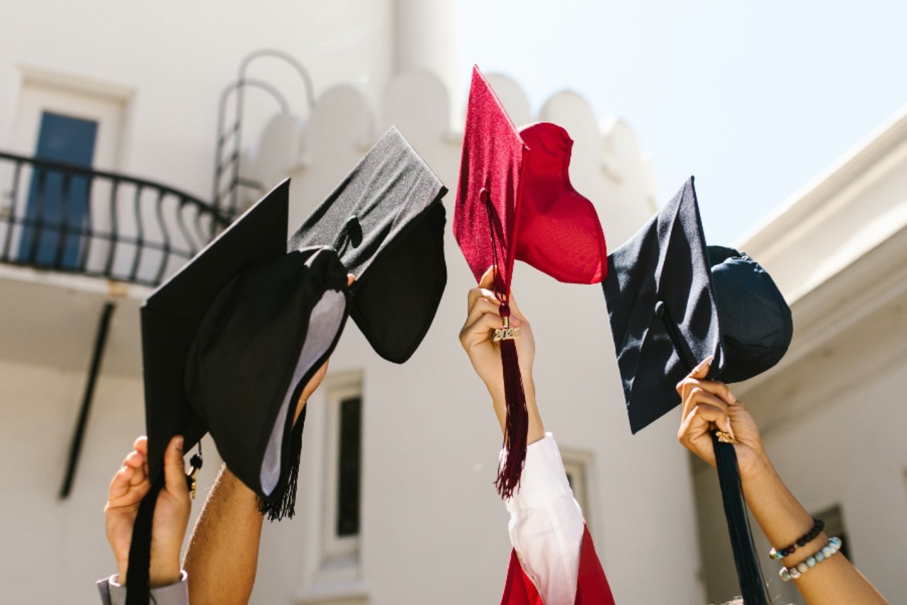 A group of graduates prepares to throw their caps in celebration