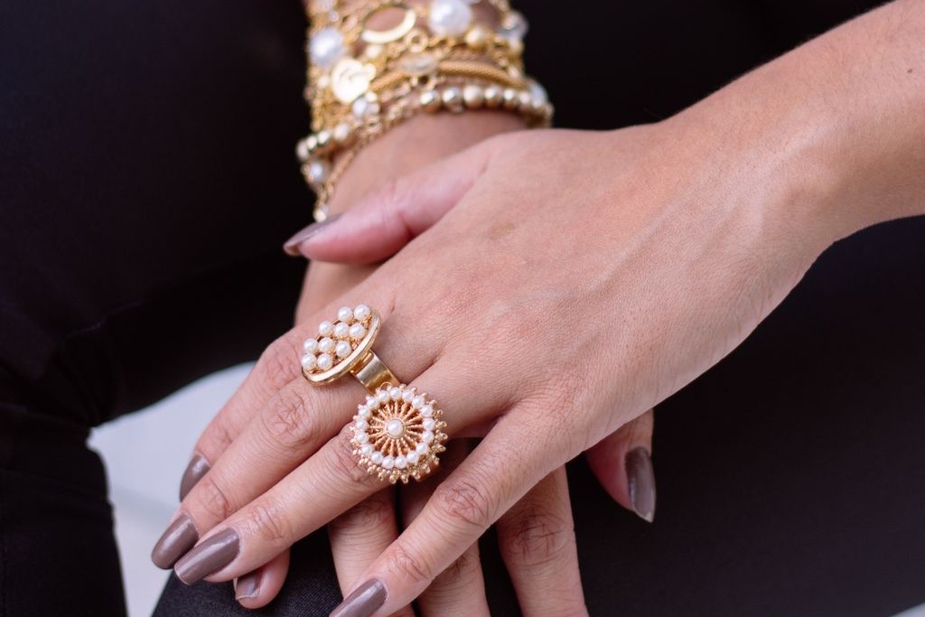 A woman sports many gold and pearl jewellery pieces, including rings and bracelets