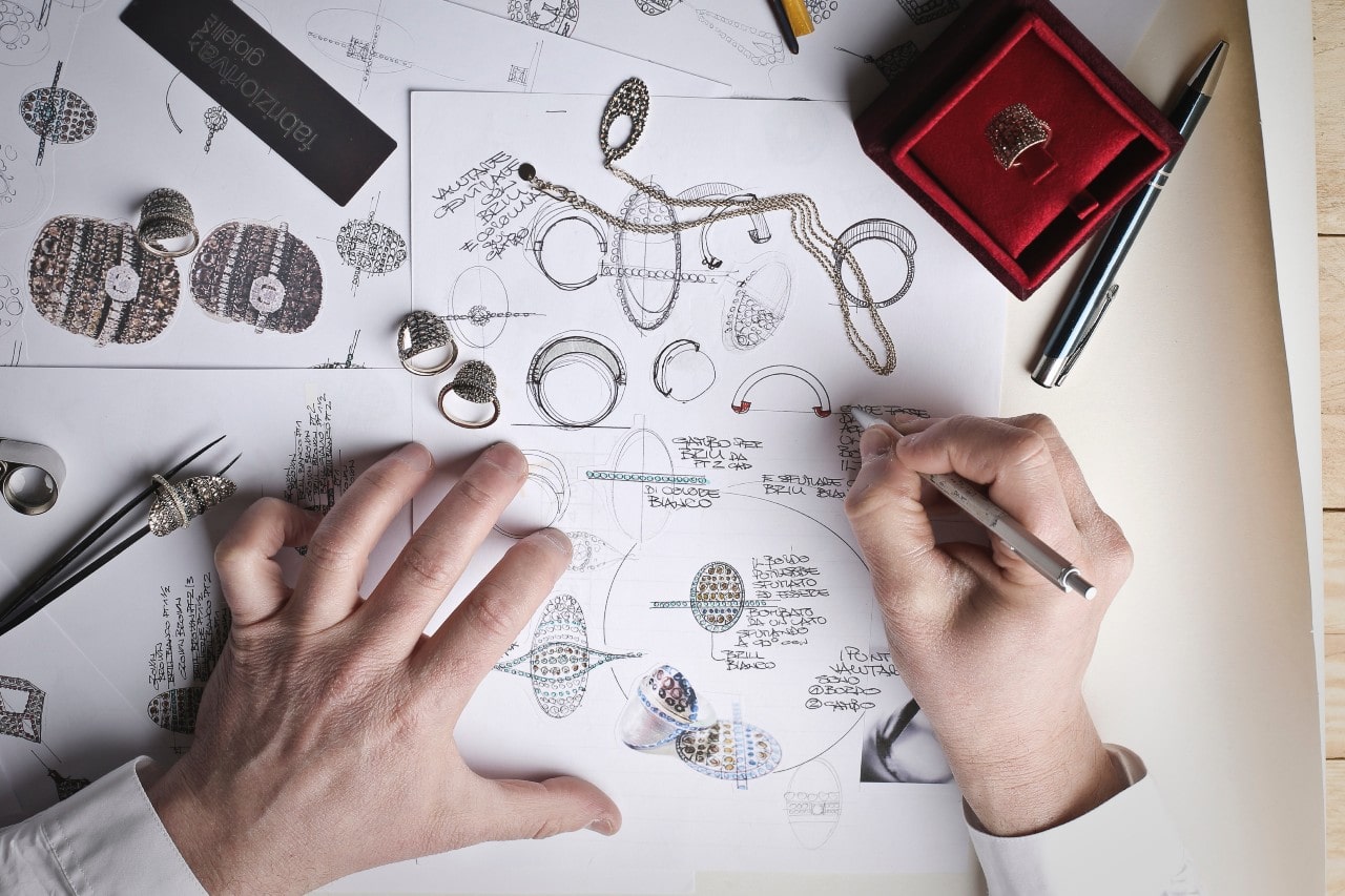 An overhead shot of a jeweller sketching jewelry designs. An overhead shot of a jeweller sketching jewelry designs.