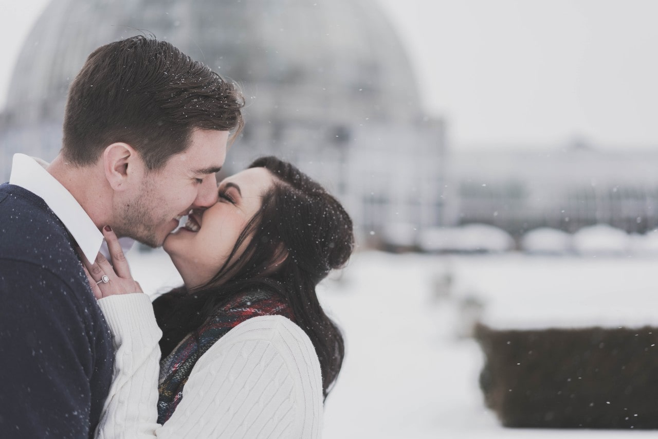 couple embracing in the snow with engagement ring