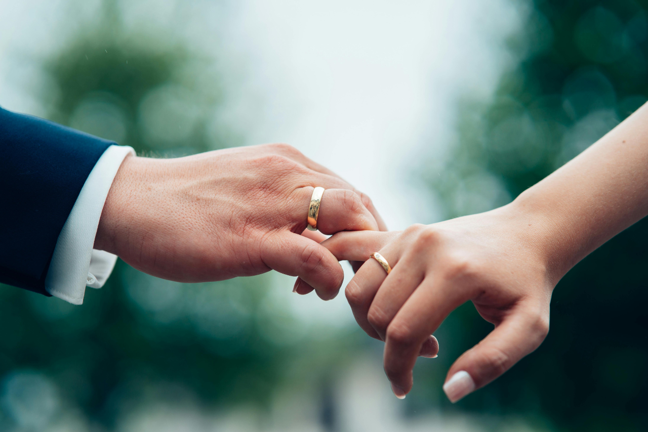 Two intertwining hands with yellow gold wedding bands. Two intertwining hands with yellow gold wedding bands.